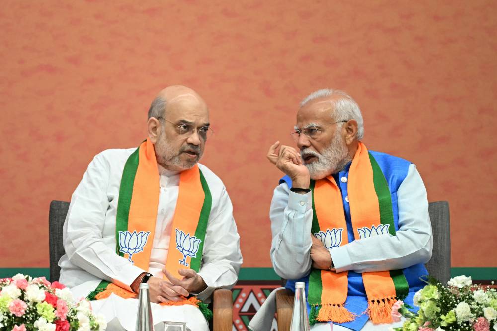 India's Home Minister Amit Shah (L) listens to Prime Minister Narendra Modi during the release of the Bharatiya Janata Party's (BJP) manifesto ahead of country's upcoming general elections, at the party headquarters in New Delhi on April 14, 2024. (Photo by AFP)