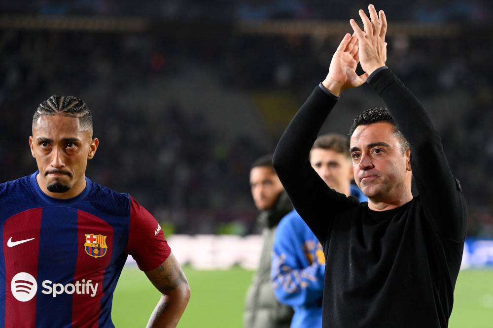Barcelona's Spanish coach Xavi applauds next to Barcelona's Brazilian forward #11 Raphinha at the end of the UEFA Champions League quarter-final second leg football match between FC Barcelona and Paris SG at the Estadi Olimpic Lluis Companys in Barcelona on April 16, 2024. Paris Saint-Germain won 1-4. (Photo by AFP)