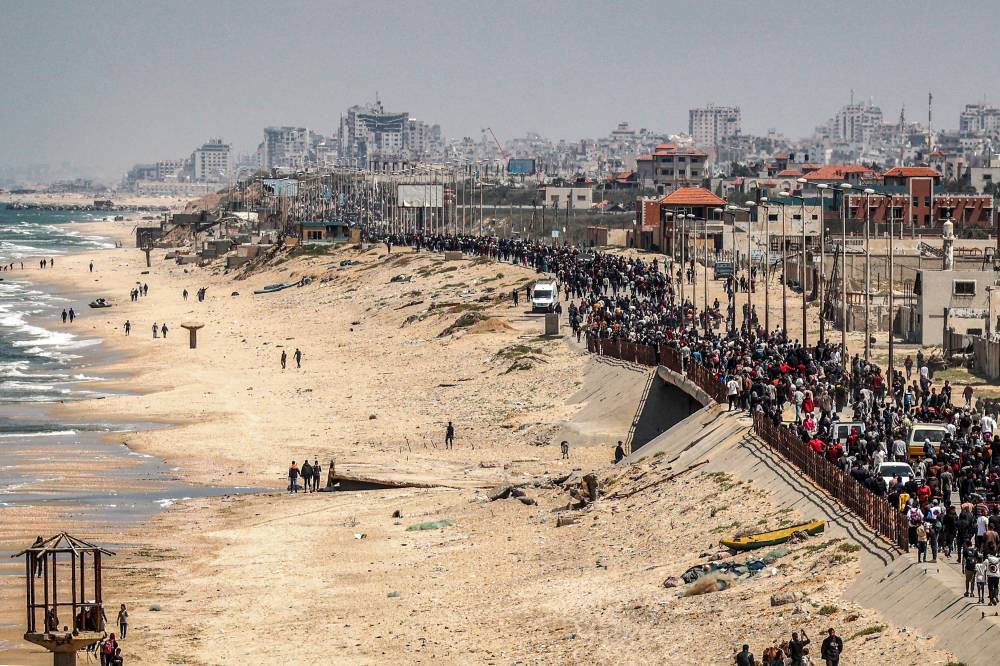 Displaced Palestinians take the coastal Rashid road to return to Gaza City as they pass through Nuseirat in the central Gaza Strip on April 14. - Photo by AFP