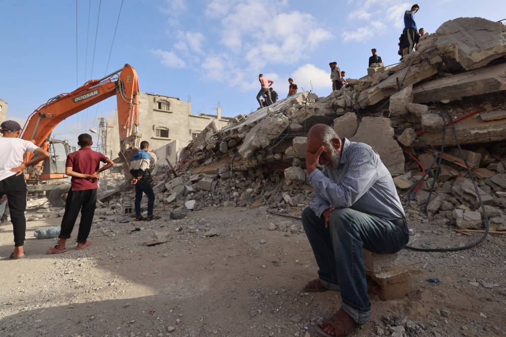 A Palestinian man wait for news of his daughter as rescue workers search for survivors under the rubble of a building hit in an overnight Israeli bombing in Rafah, in the southern Gaza Strip on April 21, 2024. - Photo by MOHAMMED ABED / AFP)