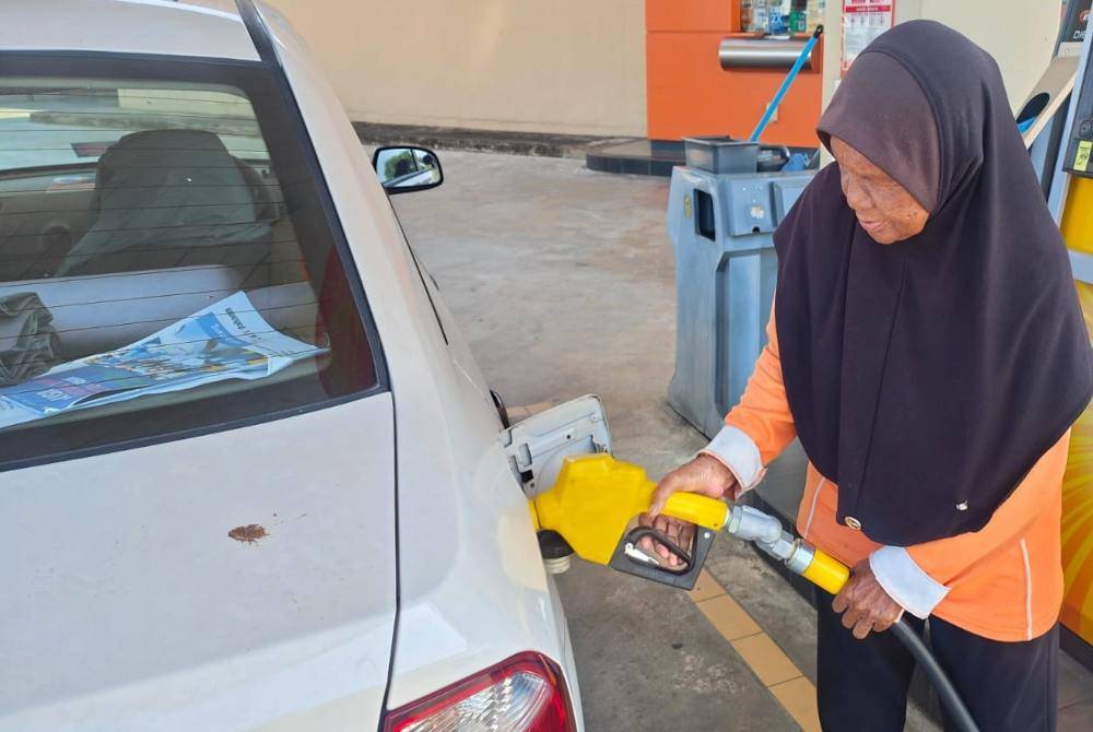 Zainab fills petrol into a vehicle's tank at a petrol station in Kuantan.