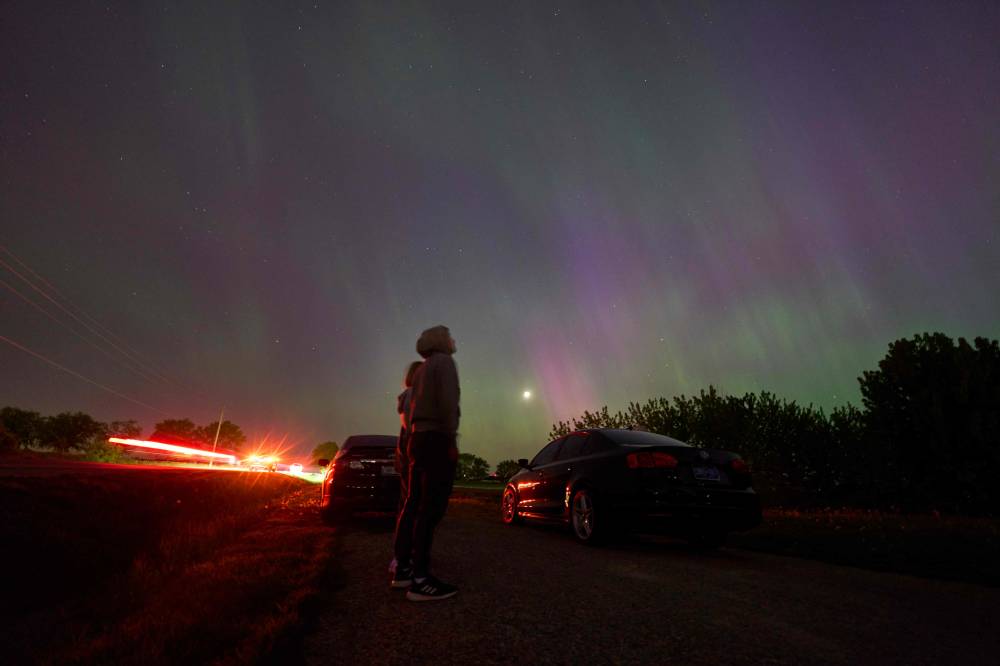 People stop along a country road near London, Ontario to watch the Northern lights or aurora borealis during a geomagnetic storm on May 10, 2024. (Photo by Geoff Robins / AFP)