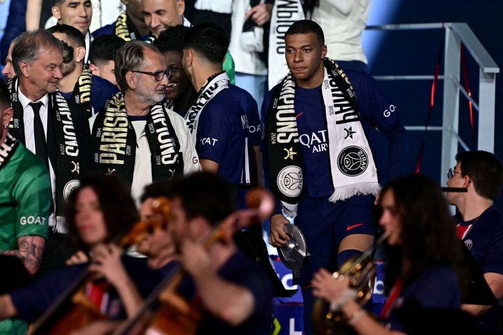 Paris Saint-Germain's French forward #07 Kylian Mbappe (R top) looks on as he celebrates with the French Ligue 1 championship's trophy during a ceremony following the French L1 football match between Paris Saint-Germain (PSG) and Toulouse (TFC) on May 12, 2024 at the Parc des Princes stadium in Paris. (Photo by AFP)