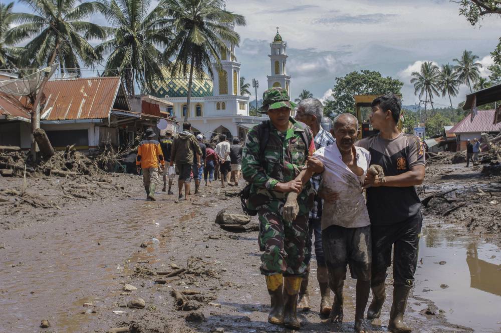 Rescuers evacuate an injured man through mud flooded area following a flash flood in Tanah Datar, West Sumatra, Indonesia. Photo by Givo Alputra/EPA