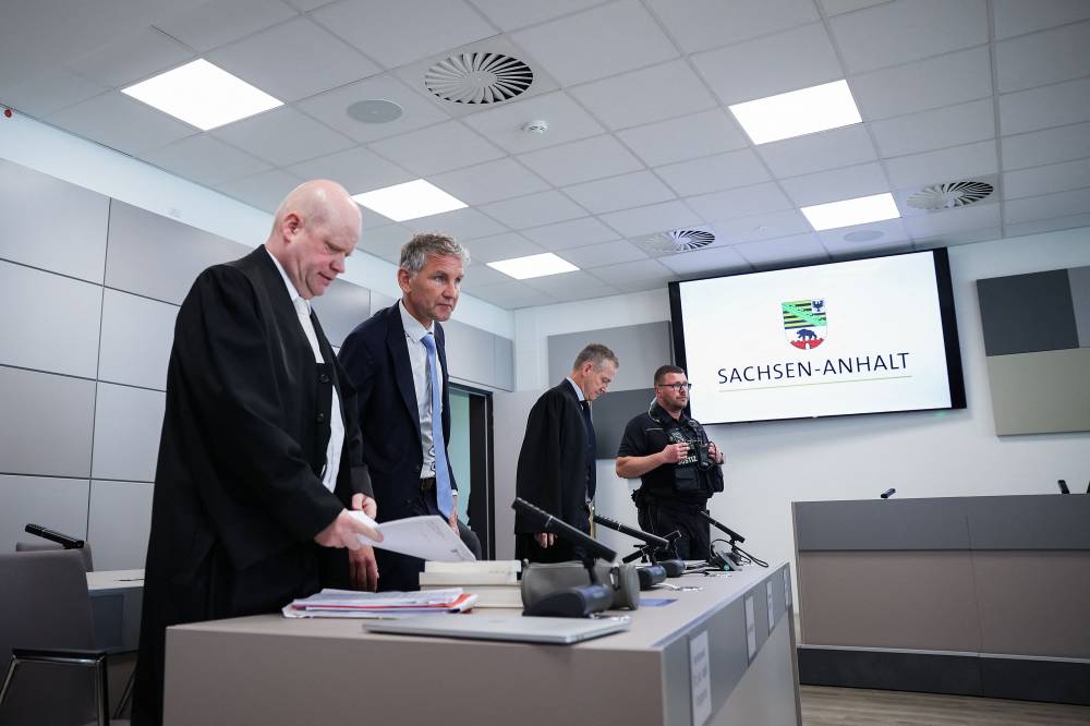 Bjoern Hoecke (2nd L), co-leader of the far-right Alternative for Germany (AfD) party in the eastern federal state of Thuringia, stands between between his lawyers Ulrich Vosgerau (L) and Ralf Hornemann (3rd L) after a break of his trial over the alleged use of Nazi phrases, at the regional court in Halle, eastern Germany on May 14, 2024. - Photo by AFP