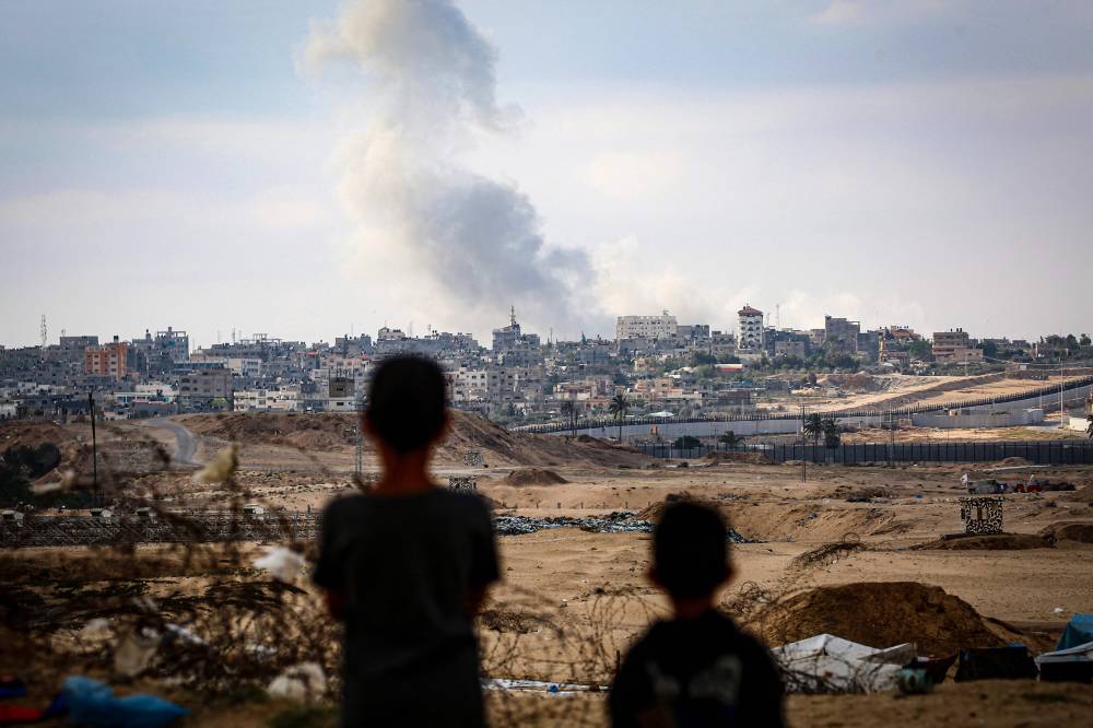Boys watch smoke billowing during Israeli strikes east of Rafah in the southern Gaza Strip on May 13, 2024. (Photo by AFP)
