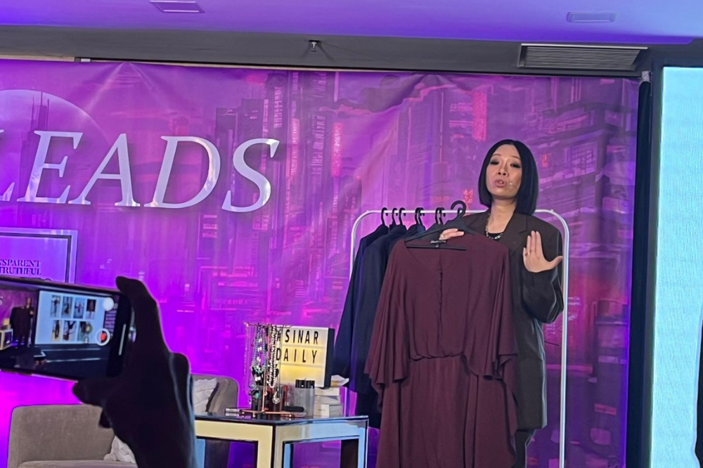 Wong holding a burgundy coloured dress as one of the example of universal colours for corporate outfit at Sinar Daily She Leads 2 event.