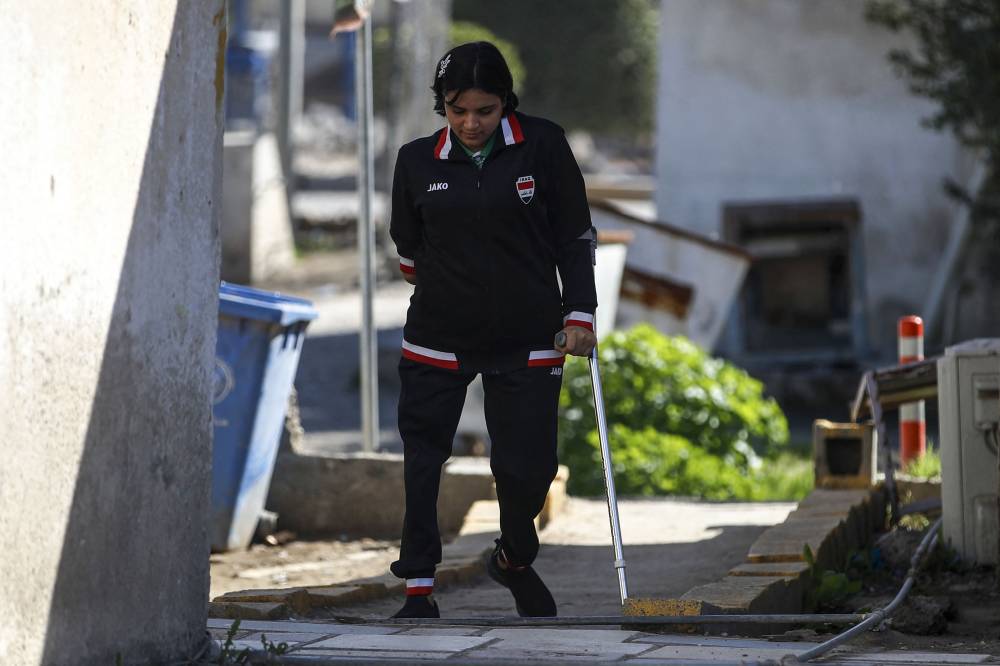 Iraqi paralympics table tennis athlete Najla Imad, walks outside her house in Baqubah, on February 26, 2024. - Photo by AFP