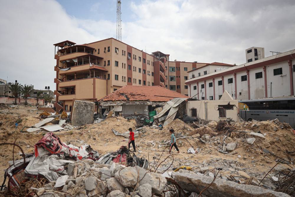 Palestinians walk on a ravaged road in front of Nasser Hospital in Khan Yunis in the southern Gaza Strip on May 2, 2024. - (Photo by AFP)