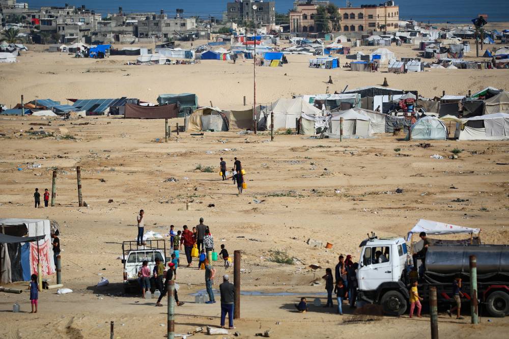 Displaced Palestinians carry water cans back to their tents at a temporary camp in Rafah on May 17, 2024. - (Photo by AFP)