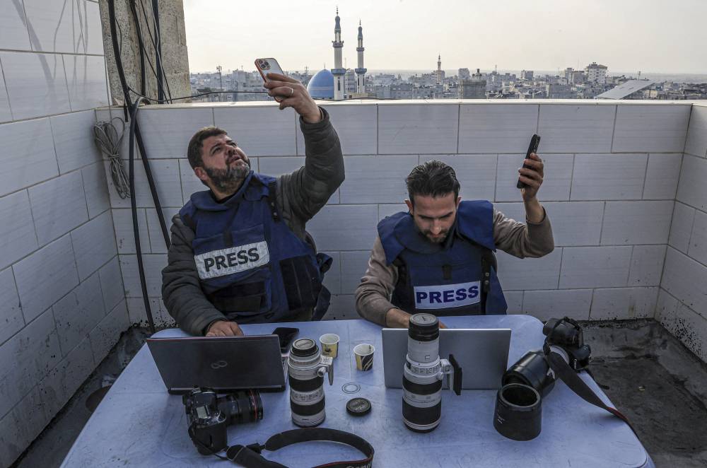 Palestinian journalists attempt to connect to the internet using their phones in Rafah on the southern Gaza Strip on Dec 27, 2023. (Photo by SAID KHATIB / AFP)