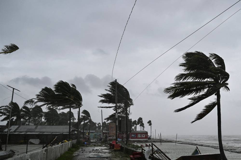 Trees sway in the wind following the landfall of Cyclone Remal, at a beach in Kuakata on May 27, 2024. Residents of low-lying coastal areas of Bangladesh and India surveyed the damage on May 27 as an intense cyclone weakened into heavy storm, with at least two people dead, roofs ripped off and trees uprooted. - (Photo by MUNIR UZ ZAMAN / AFP)