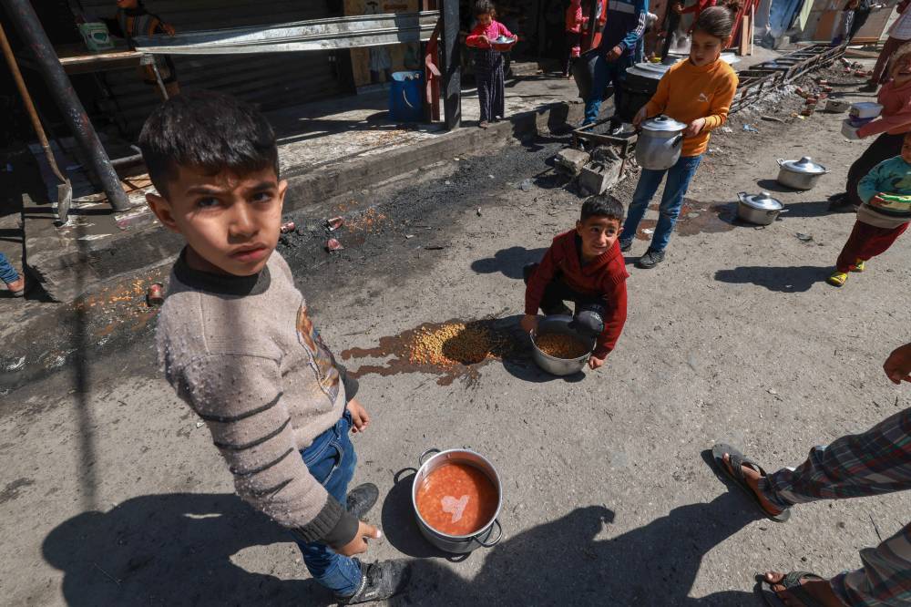 Palestinian children receive cooked food rations as part of a volunteer youth initiative in Rafah in the southern Gaza Strip, on March 5, 2024, amid widespread hunger in the besieged Palestinian territory. - (Photo by MOHAMMED ABED / AFP)