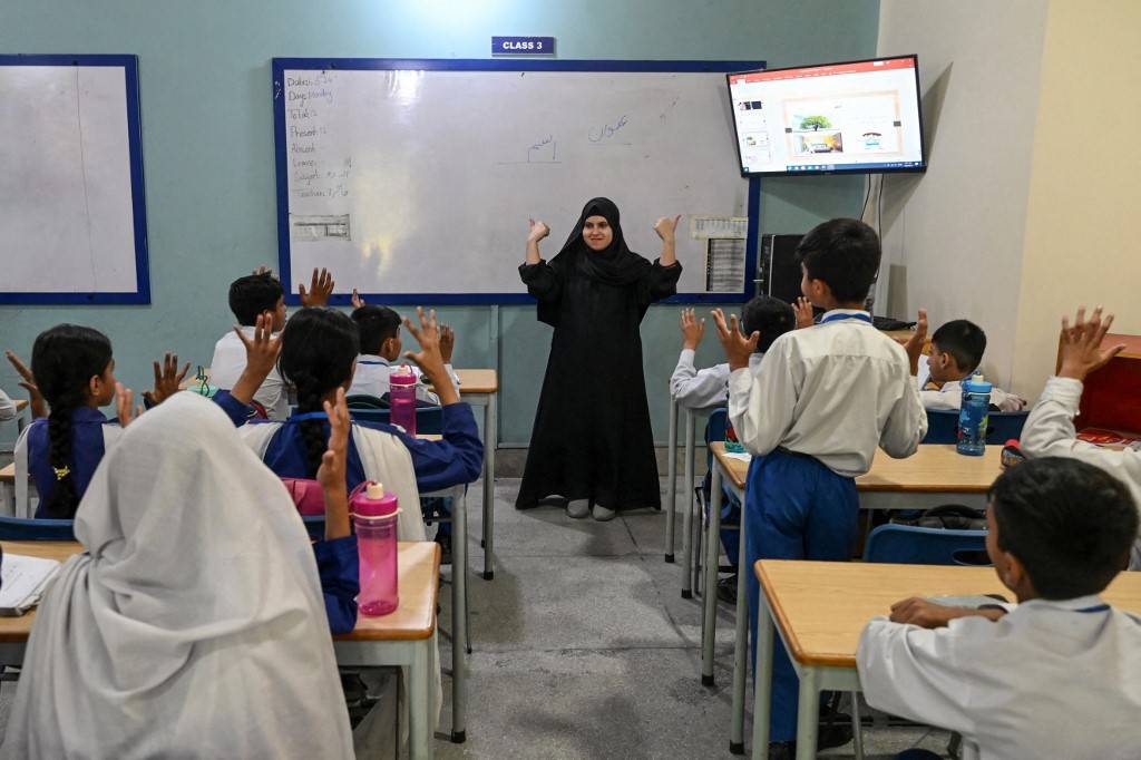 A teacher (C) leading a class of hearing-impaired students at a school run by the charity Deaf Reach, Photo by Arif Ali/AFP