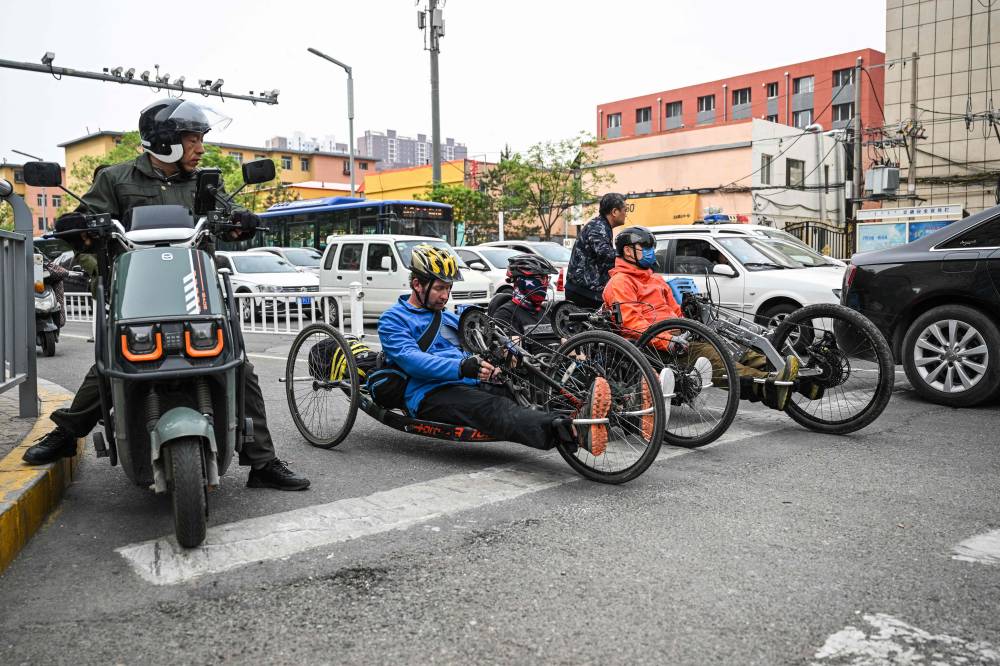 Pan Yifei (right), Wang Feng(centre) and Joshua Dominick (left) ride handcycles on a street in Hohhot, in China's northern Inner Mongolia region. Photo by Hector Retamal/AFP