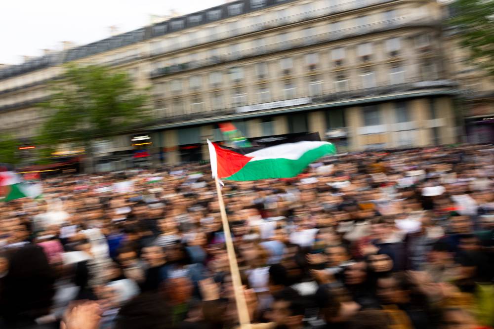 A protester waves a Palestinian flag over the crowd at Place de la Republique, during a demonstration to show support to Palestinians in Paris on May 28, 2024. - (Photo by ANTONIN UTZ / AFP)