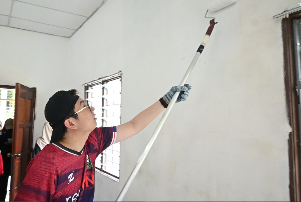 A volunteer painting the wall.