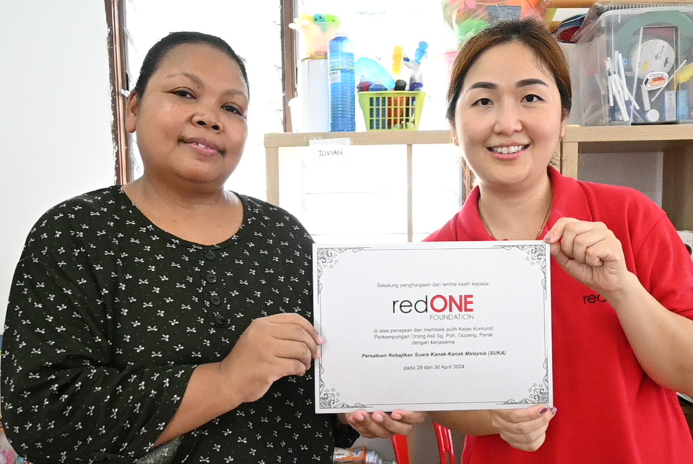 redONE mobile Head of Corporate Governance Caren Lwee presenting appreciation plaque to Cikgu Dinah from Sg Poh Community School