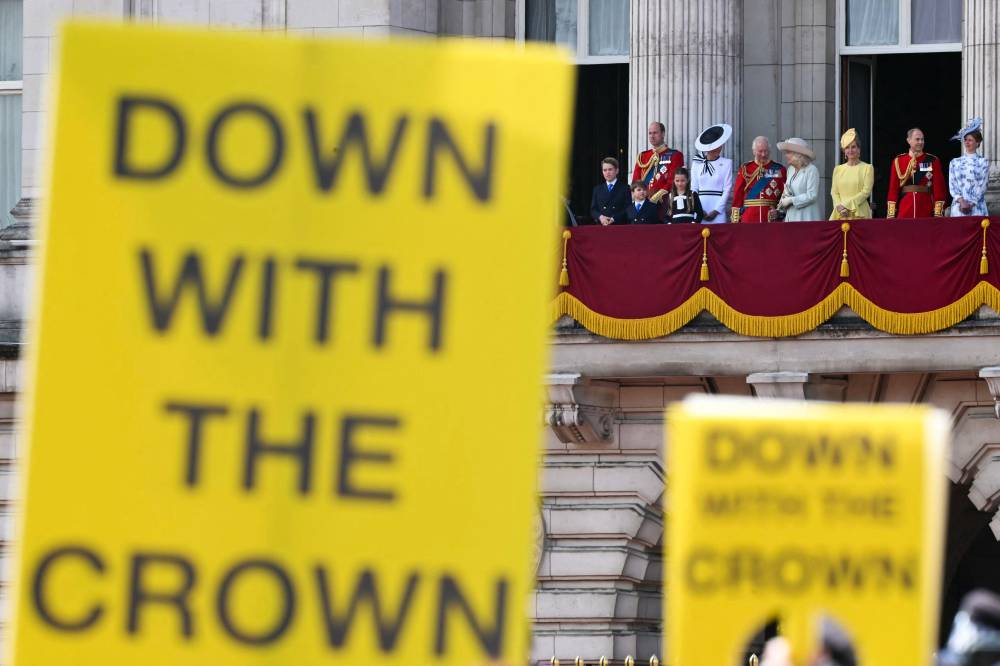 Protesters from the anti-monarchy group Republic, hold placards outside Buckingham Palace as Britain's King Charles III and members of the royal family stand on the balcony after the King's Birthday Parade, "Trooping the Colour", in London, on June 15, 2024. (Photo by JUSTIN TALLIS / AFP)