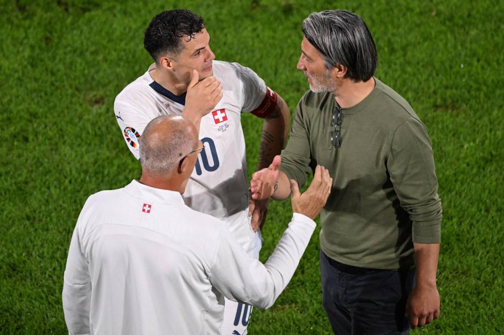 Switzerland's midfielder #10 Granit Xhaka speaks with Switzerland's head coach Murat Yakin (R) at the end of the UEFA Euro 2024 Group A football match between Scotland and Switzerland at the Cologne Stadium in Cologne on June 19, 2024. (Photo by AFP)