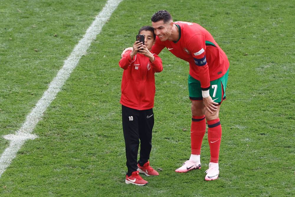 A pitch invader takes his selfie with Portugal's forward #07 Cristiano Ronaldo during the UEFA Euro 2024 Group F football match between Turkey and Portugal at the BVB Stadion in Dortmund on June 22, 2024. (Photo by AFP)