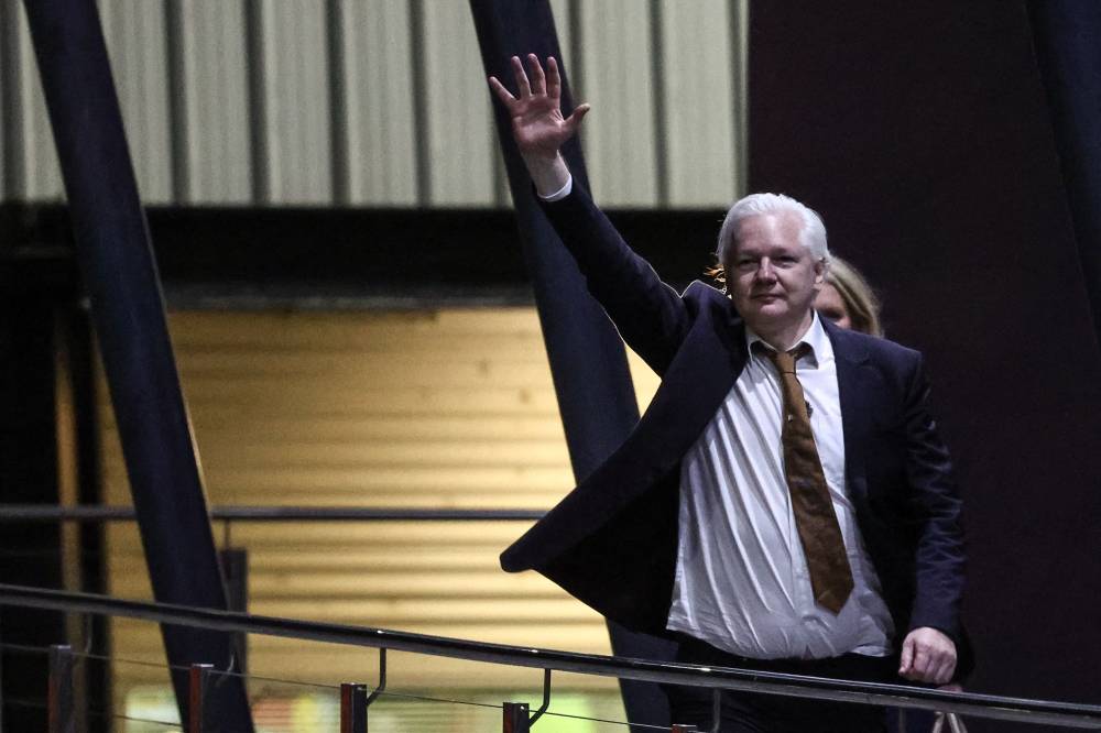 WikiLeaks founder Julian Assange waves after arriving at Canberra Airport in Canberra. Photo by David Gray/AFP