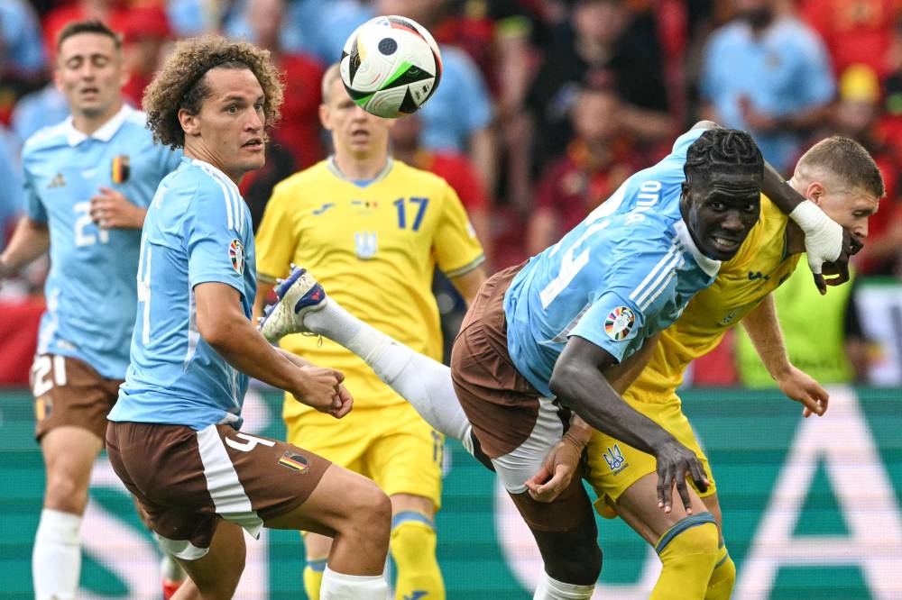 Belgium's midfielder #24 Amadou Onana heads the ball past Ukraine's forward #11 Artem Dovbyk as Belgium's defender #04 Wout Faes watches during the UEFA Euro 2024 Group E football match between Ukraine and Belgium at the Stuttgart Arena in Stuttgart. Photo by Thomas Kienzle/AFP