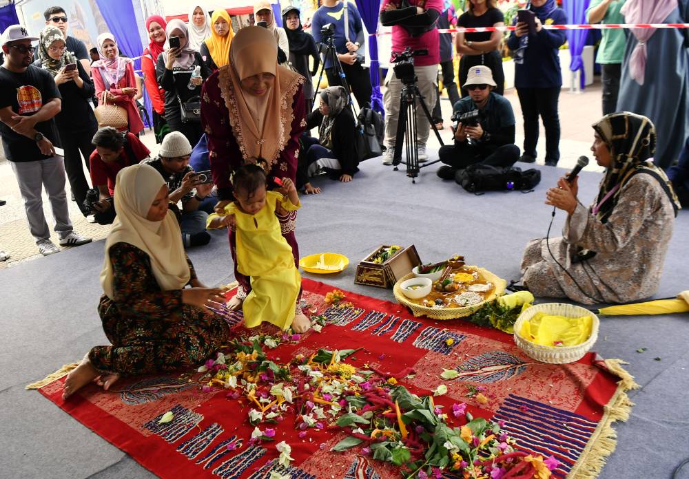 'Adat Berjojak' ritual symbolises a baby’s first step in life and only after the ceremony is performed can the feet of the child touch the ground outside the house. Photo by Bernama