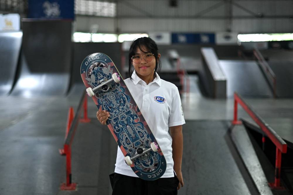 This photo taken on June 27, 2024 shows 12-year-old Thai skateboarder Vareeraya Sukasem posing for a photograph ahead of a training session at Hua Mak skate park in Bangkok. - (Photo by MANAN VATSYAYANA / AFP)