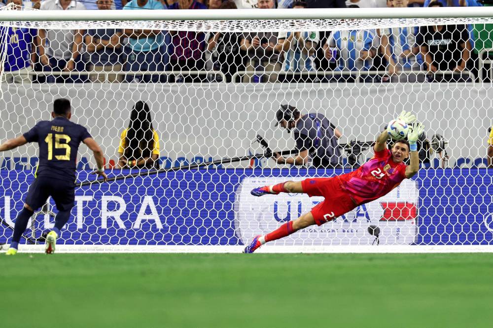 Argentina's goalkeeper #23 Emiliano Martinez saves a goal from the penalty spot from Ecuador's midfielder #15 Angel Mena in a penalty shoot out during the Conmebol 2024 Copa America tournament quarter-final football match between Argentina and Ecuador at NRG Stadium in Houston, Texas, on July 4, 2024. (Photo by AFP)