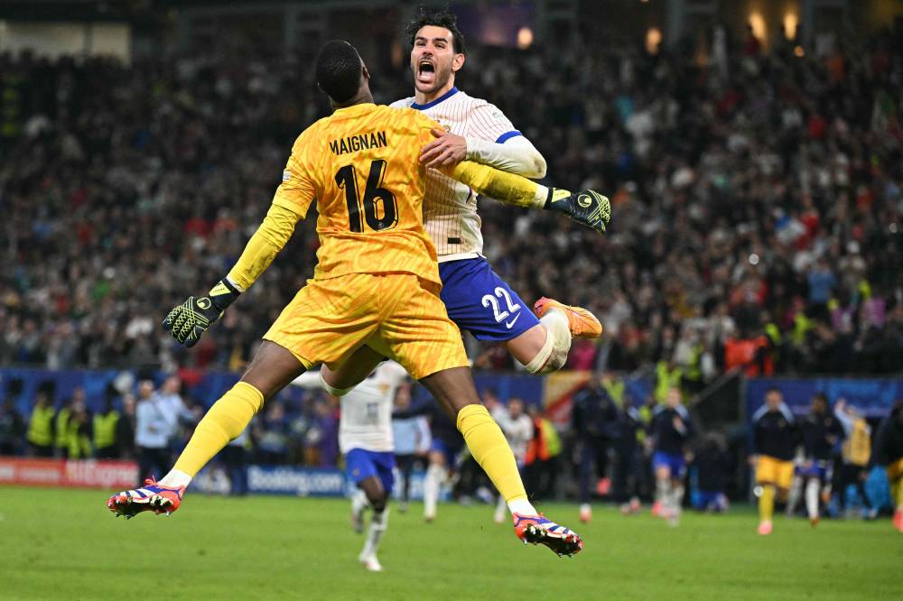 France's defender #22 Theo Hernandez celebrates with France's goalkeeper #16 Mike Maignan after he scored his penalty and qualified France during the UEFA Euro 2024 quarter-final football match between Portugal and France at the Volksparkstadion in Hamburg. Photo by Javier Soriano/AFP