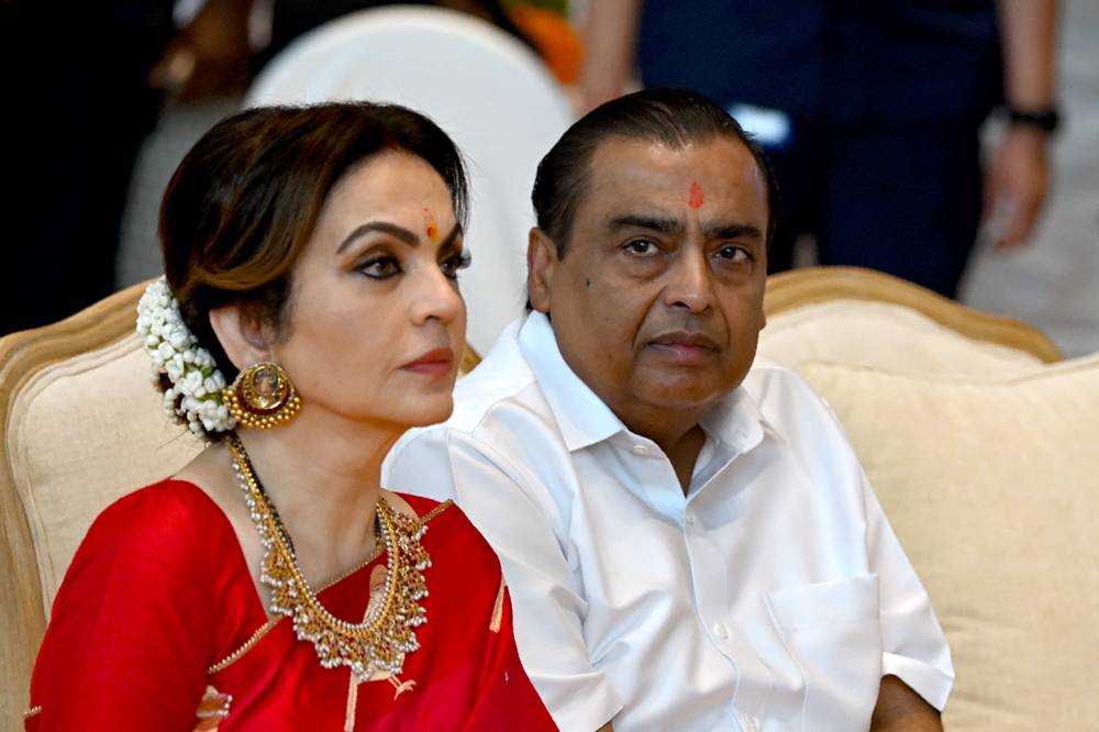 Billionaire tycoon and Chairman of Reliance Industries Mukesh Ambani (R) with his wife Nita Ambani attends a mass wedding ceremony of underprivileged couples ahead of their son Anant Ambani's wedding to Radhika Merchant, at Reliance Corporate Park in Navi Mumbai on July 2, 2024. - (Photo by PUNIT PARANJPE / AFP)