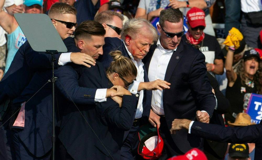Republican candidate Donald Trump is seen with blood on his face surrounded by secret service agents as he is taken off the stage at a campaign event at Butler Farm Show Inc. in Butler, Pennsylvania, July 13, 2024. - (Photo by REBECCA DROKE / AFP)