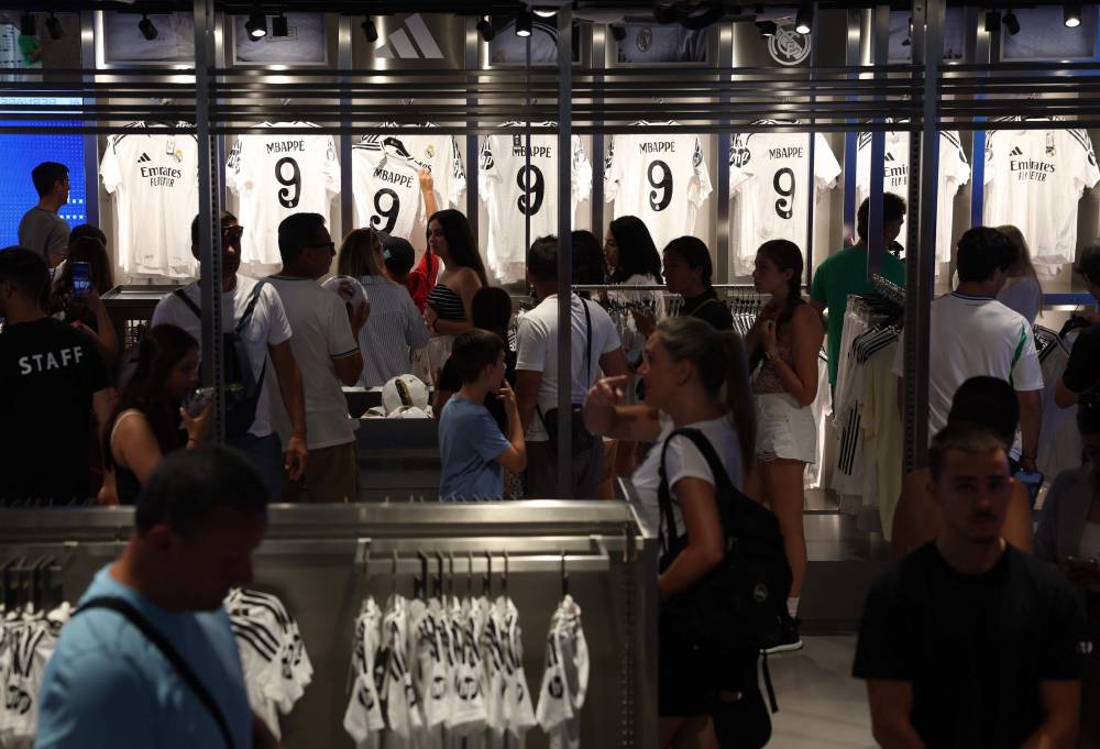 People buy the newly launched jersey of French footballer Killyan Mbappe at the Real Madrid's official store in the Santiago Bernabeu stadium in Madrid on July 11, 2024. (Photo by AFP)