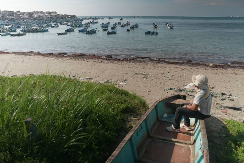 A fisherman sits in a boat at the beach in the Santa Rosa fishing port in Salinas, Ecuador, on June 26, 2024. - Photo by AFP