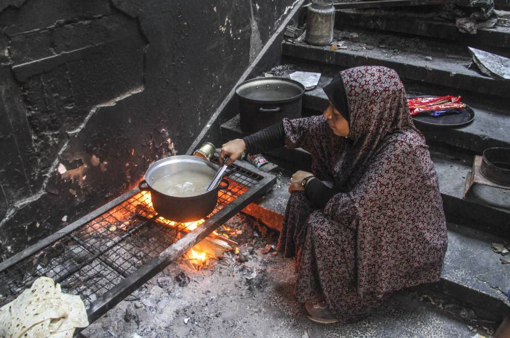 A family member of Ahmed Shinbari boils water in the northern parts of Gaza, on July 17, 2024. - Photo by Xinhua