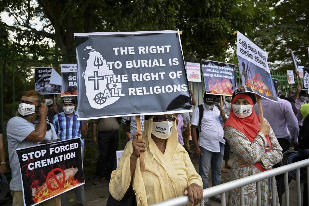 Protesters hold placards during a demonstration against the government policy of forced cremations of Muslims who died of the Covid-19 coronavirus, outside a cemetery in Colombo on December 31, 2020. (Photo by ISHARA S. KODIKARA / AFP)
