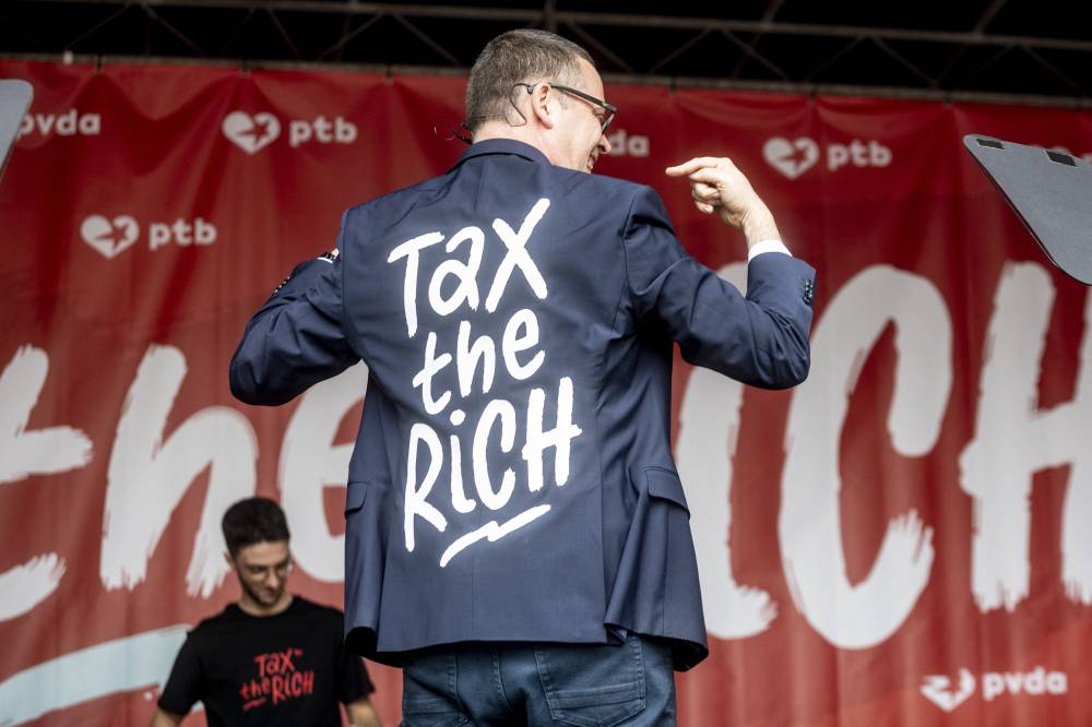 FILES: PTB chairman Raoul Hedebouw gestures while wearing a vest reading 'Tax the rich' at the meeting of leftist party PVDA - PTB in Brussels, on Labour Day, the International Workers' Day, on May 1, 2023. (Photo by HATIM KAGHAT / Belga / AFP) 
