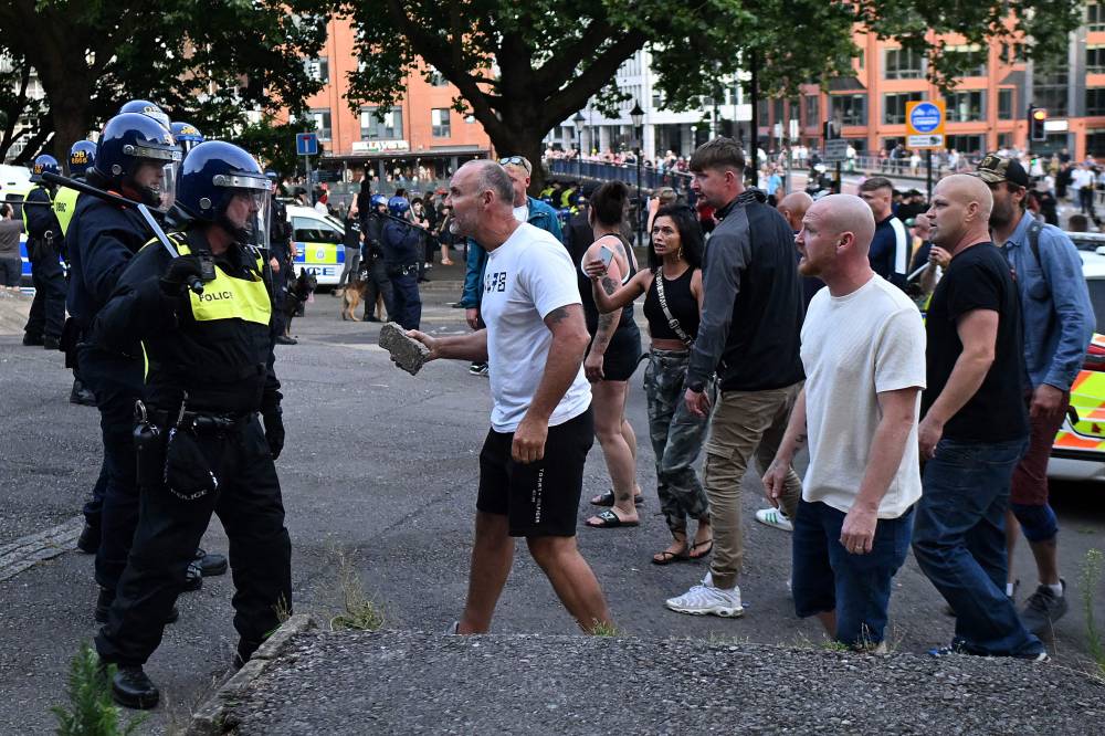 A protester holding a piece of concrete walks towards riot police as clashes erupt in Bristol on August 3, 2024 during the 'Enough is Enough' demonstration held in reaction to the fatal stabbings in Southport on July 29. - Photo by AFP