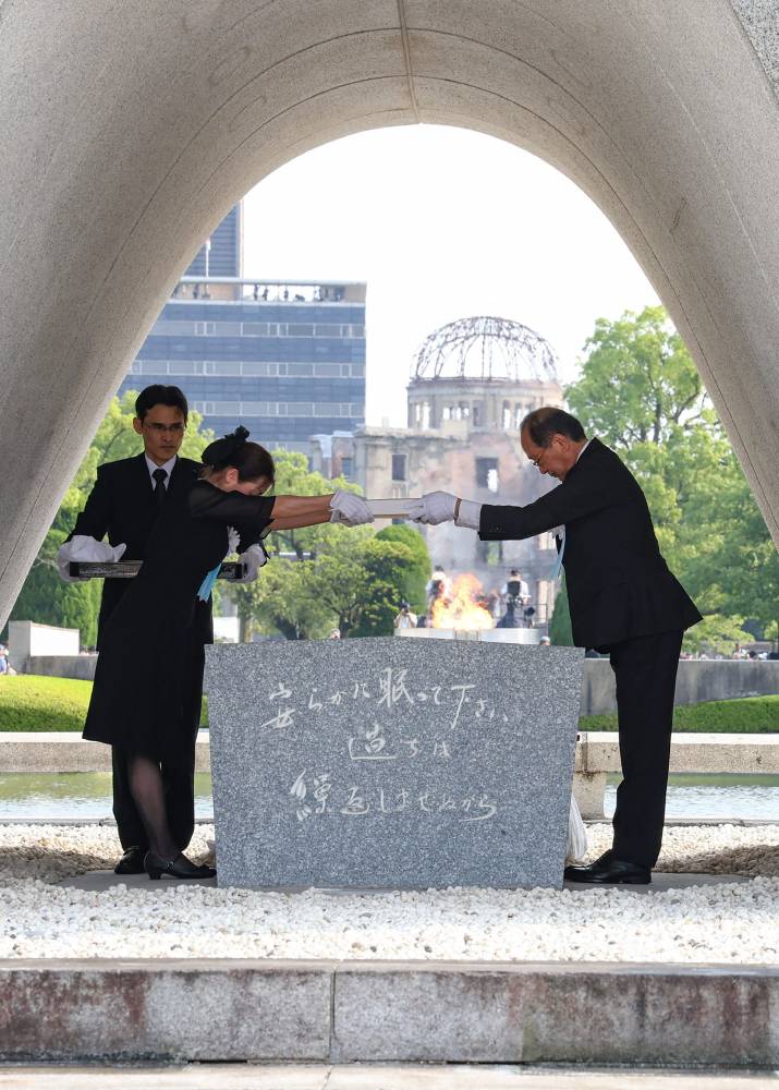 Hiroshima City Mayor Kazumi Matsui (R) and a representative of the bereaved families (L) place a list of atomic bomb victims at the Cenotaph during the Peace Memorial Ceremony at the Peace Memorial Park in Hiroshima on August 6, 2024, to mark the 79th anniversary of the world's first atomic bomb attack. (Photo by AFP) 