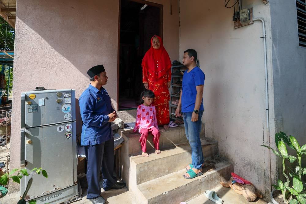 Terengganu Islamic Propagation Foundation of Malaysia (Yadim) director Nasrul Hadi Saiadin (left) visits the family of Wan Khairu (right), who had to quit his job to care for his mother. Photo by Bernama