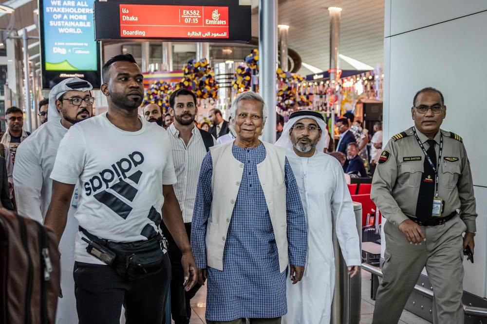 Nobel laureate Muhammad Yunus (C) is escorted by Emirates security personnel as he walks at the Dubai International Airport before boarding his flight to Dhaka, in Dubai on August 8, 2024. Nobel peace prize winner Muhammad Yunus was flying back to Bangladesh on August 8 to lead a caretaker government after a student-led uprising ended the 15-year rule of Sheikh Hasina. (Photo by AFP)