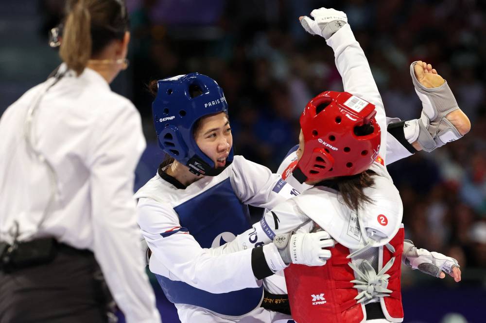 Thailand's Panipak Wongpattanakit (C) and China's Guo Qing compete in the taekwondo women's -49kg gold medal bout of the Paris 2024 Olympic Games at the Grand Palais in Paris on August 7, 2024. (Photo by AFP)