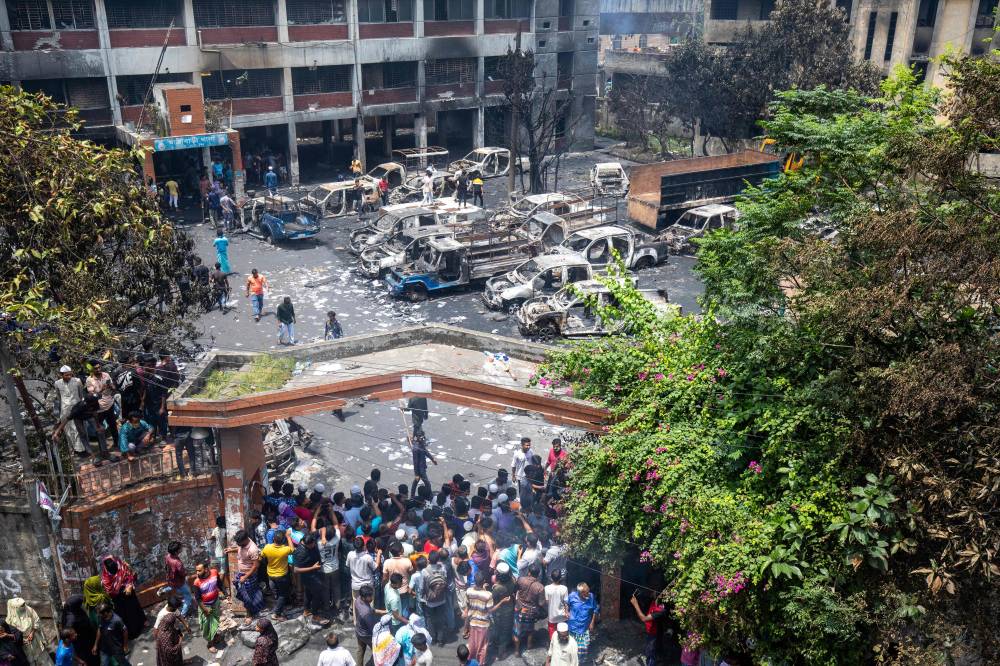 People gather to see burnt Jatrabari police station as anti-government protestors set fire in Dhaka, central Bangladesh on Aug 6, 2024, after former prime minister Sheikh Hasina fled the country. - Photo by AFP