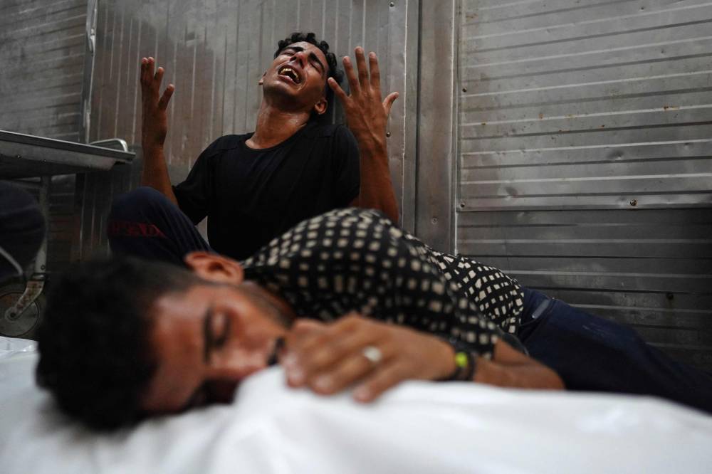 Palestinians mourn over a body of a relative, killed in an Israeli strike Photo by Bashar Taleb/AFP