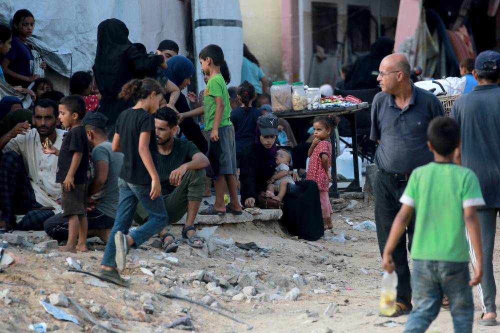 Palestinian families rest along a street as thousands of Palestinians who fled following the Israeli army's temporary evacuation order for parts of Khan Yunis, including the Al-Mawasi humanitarian zone, arrive in an another area of the southern Gaza Strip city on July 23, 2024. - (Photo by Bashar TALEB / AFP)