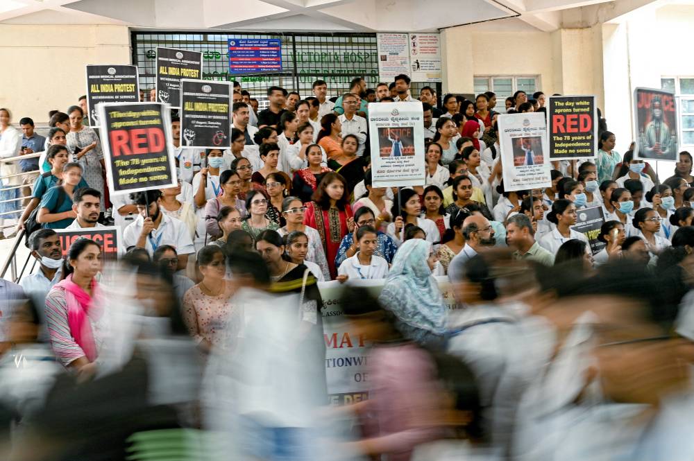 Medical professionals hold posters amid nationwide strike by doctors to condemn the rape and murder of a young medic from Kolkata, at a hospital in Bengaluru on Aug 17, 2024. - (Photo by IDREES MOHAMMED / AFP)