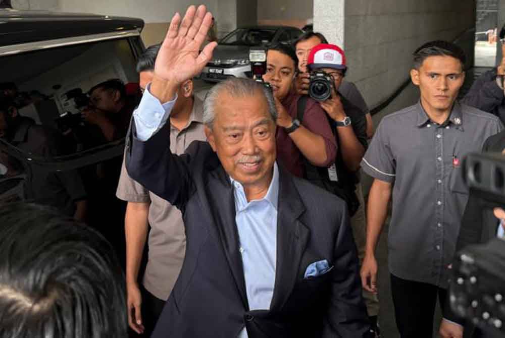 Muhyiddin waving to media personnel after completing his statement to the police on Wednesday.