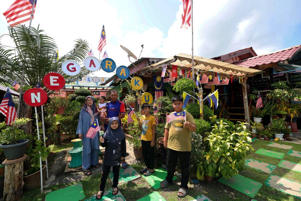 Outside Aziz's home, a captivating display of the Jalur Gemilang greets visitors with three small gazebos, two adorned with images depicting the nation's independence, creating a mini garden ambience. Photo by Bernama