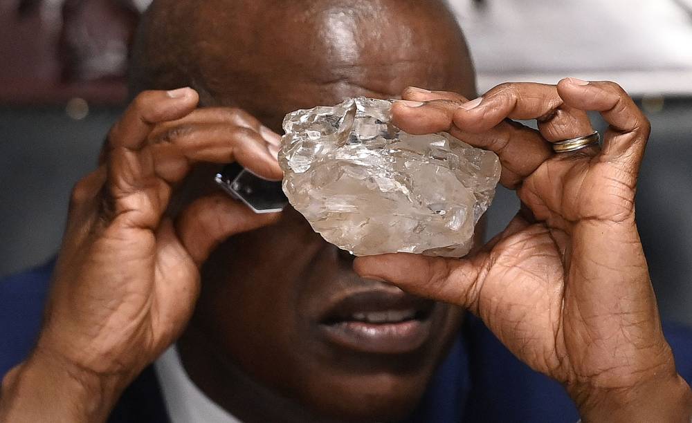 Botswana's President Mokgweetsi Masisi looks at a large diamond discovered in Botswana at his office in Gaborone on August 22, 2024. - Photo by AFP